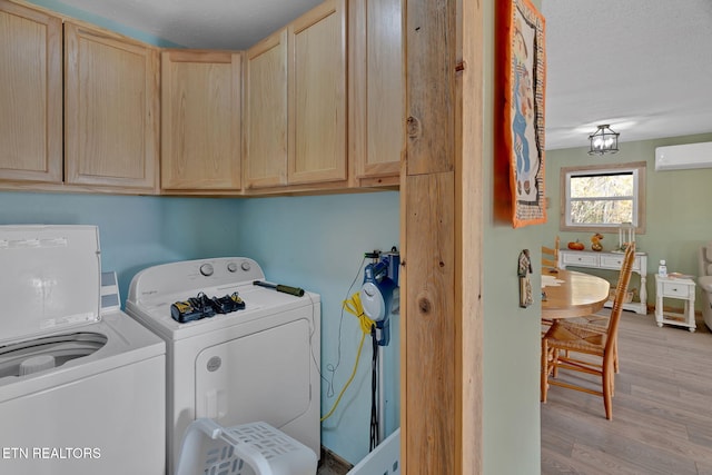 washroom featuring light wood-type flooring, cabinets, washing machine and clothes dryer, and a wall unit AC