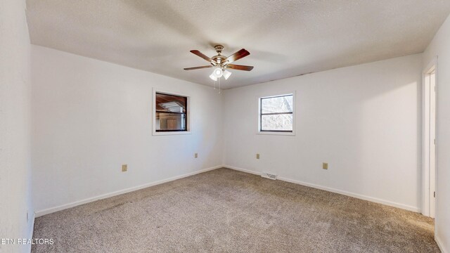 carpeted spare room featuring ceiling fan and a textured ceiling