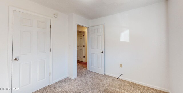 unfurnished bedroom featuring light colored carpet and a closet