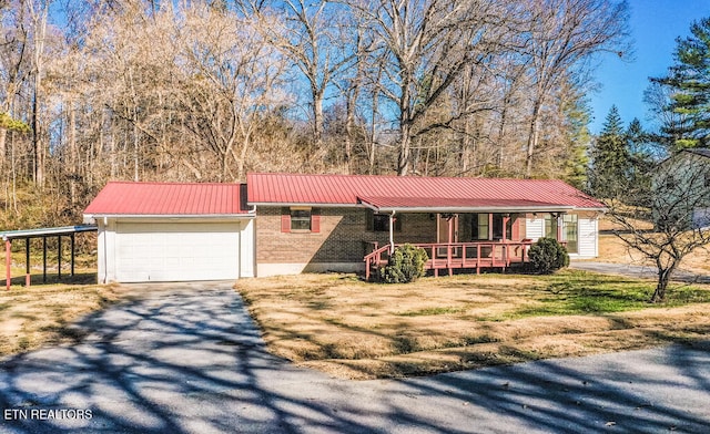 single story home featuring a garage, a front yard, covered porch, and a carport