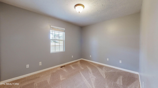 carpeted empty room with a textured ceiling