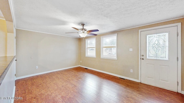 entryway with ornamental molding, hardwood / wood-style floors, ceiling fan, and a textured ceiling