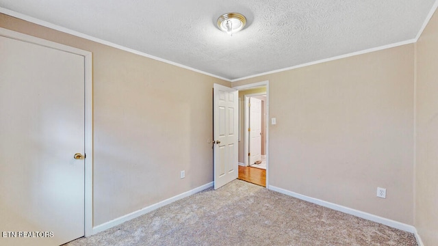 unfurnished bedroom with light colored carpet, a textured ceiling, and crown molding