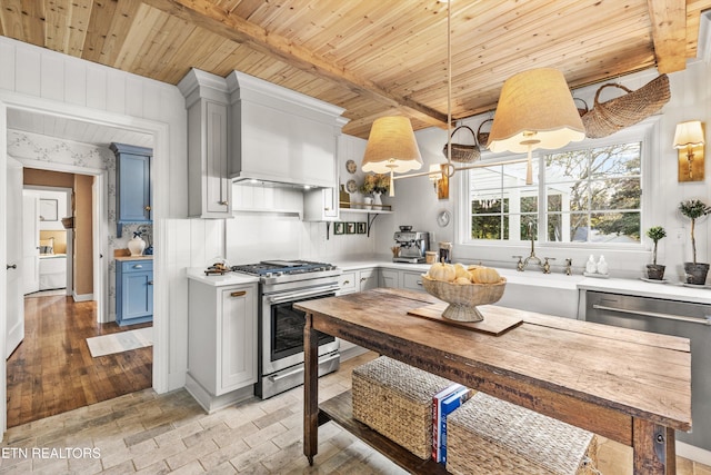 kitchen featuring stainless steel appliances, blue cabinets, decorative light fixtures, wooden ceiling, and wall chimney exhaust hood