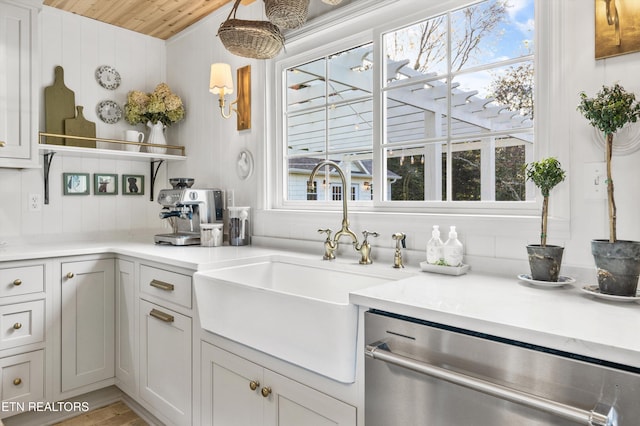 kitchen with hanging light fixtures, light stone countertops, sink, and stainless steel dishwasher