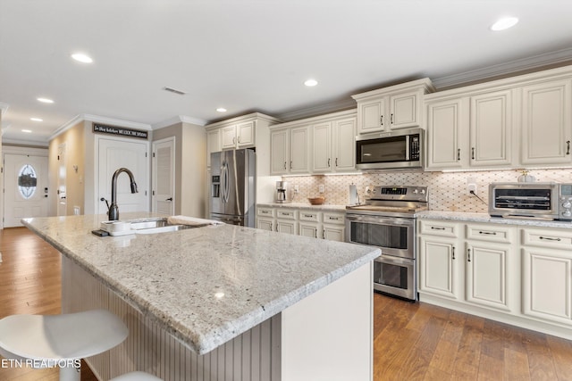 kitchen featuring appliances with stainless steel finishes, light stone counters, dark wood-type flooring, and an island with sink