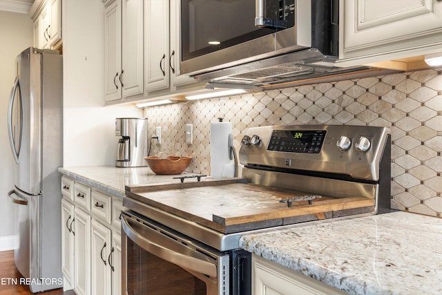 kitchen with light stone countertops, backsplash, stainless steel appliances, and dark hardwood / wood-style floors