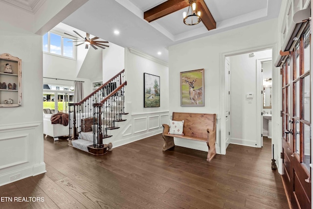 entrance foyer with dark hardwood / wood-style floors, beam ceiling, an inviting chandelier, and ornamental molding