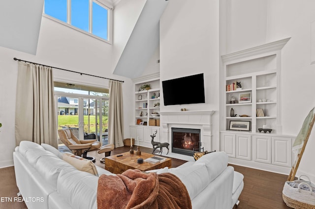 living room featuring built in features, dark wood-type flooring, and a high ceiling