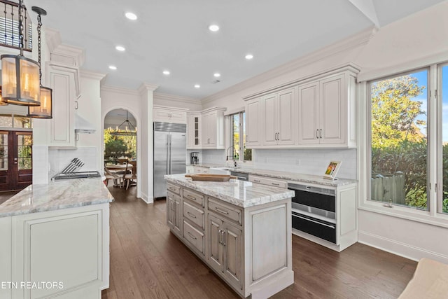 kitchen featuring dark hardwood / wood-style flooring, tasteful backsplash, appliances with stainless steel finishes, and a center island