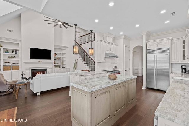 kitchen featuring dark wood-type flooring, appliances with stainless steel finishes, decorative backsplash, and light stone counters