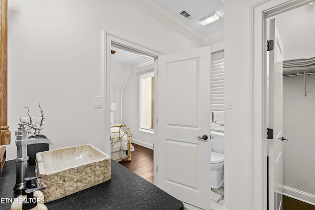 bathroom with hardwood / wood-style flooring, toilet, and ornamental molding