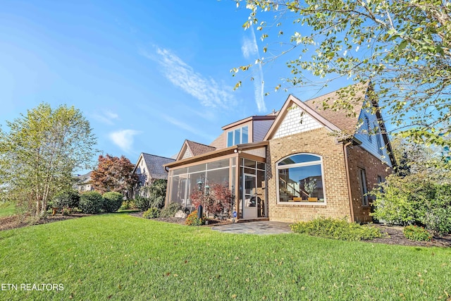 rear view of house with a patio, a sunroom, and a yard