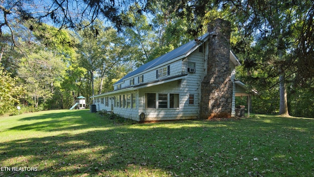 view of side of home with a lawn and a playground