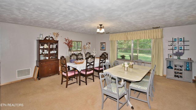 dining area with a textured ceiling and light carpet