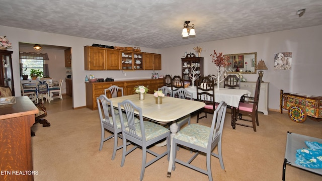 dining space with light carpet and a textured ceiling