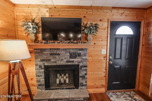 foyer entrance featuring wood walls, a stone fireplace, and hardwood / wood-style floors