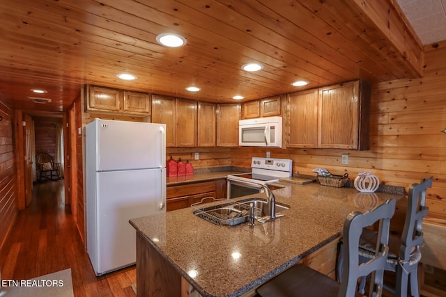 kitchen with wood walls, a breakfast bar, dark hardwood / wood-style floors, white appliances, and wood ceiling