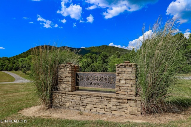 community / neighborhood sign featuring a lawn and a mountain view