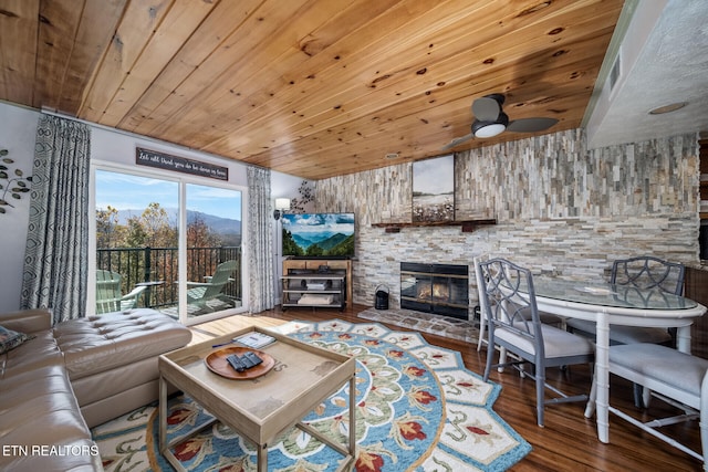 living room featuring a stone fireplace, wood ceiling, wood-type flooring, and ceiling fan