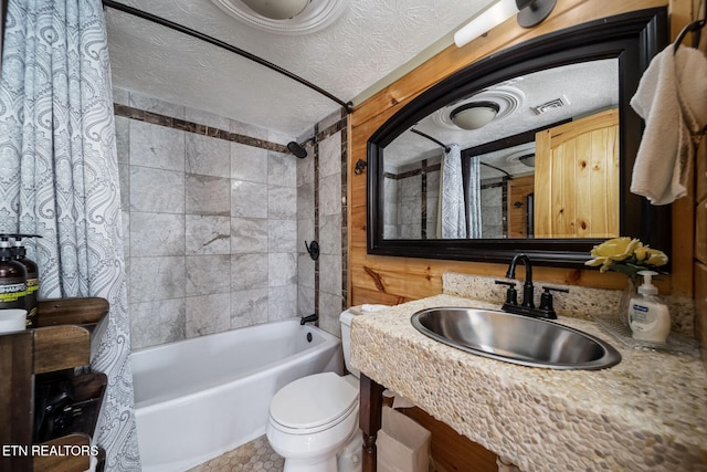 full bathroom featuring toilet, wood walls, a textured ceiling, sink, and shower / tub combo