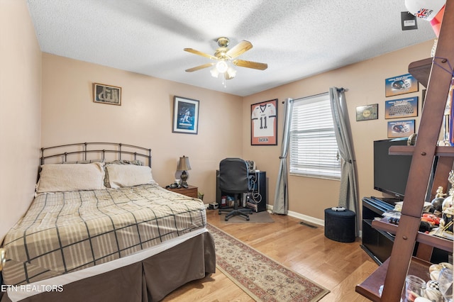 bedroom with a textured ceiling, light wood-type flooring, and ceiling fan