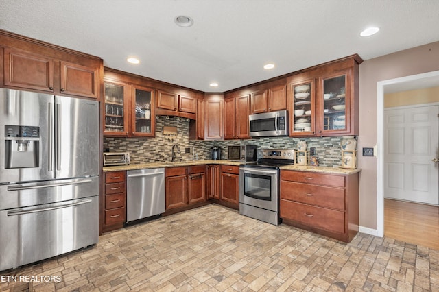 kitchen with decorative backsplash, sink, light stone counters, and appliances with stainless steel finishes