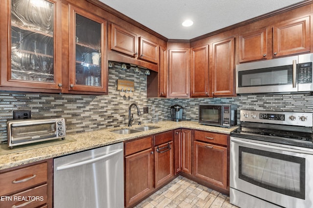 kitchen with light stone countertops, sink, tasteful backsplash, a textured ceiling, and appliances with stainless steel finishes