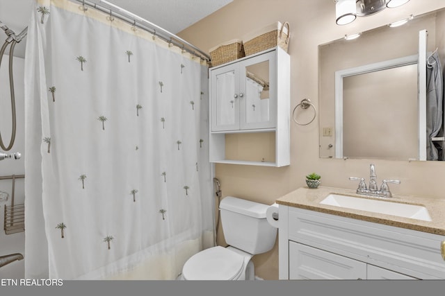 bathroom with vanity, toilet, and a textured ceiling