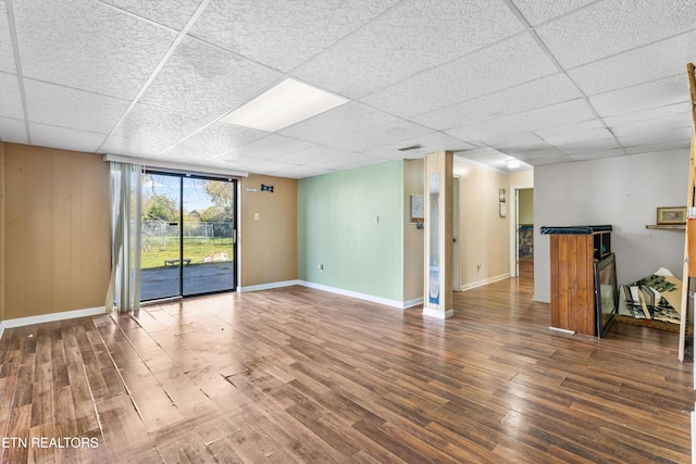 unfurnished living room featuring a drop ceiling and dark wood-type flooring