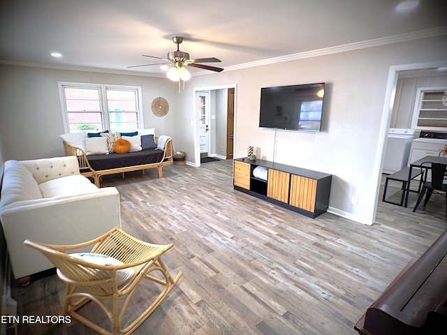 living room featuring washer / dryer, hardwood / wood-style floors, ceiling fan, and crown molding