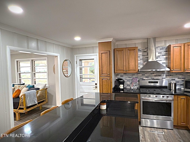 kitchen featuring wall chimney exhaust hood, crown molding, plenty of natural light, and stainless steel appliances