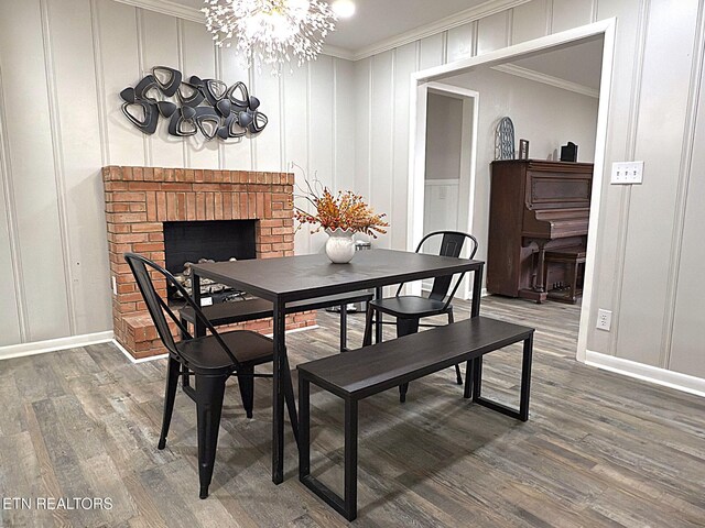 dining area featuring a fireplace, dark hardwood / wood-style flooring, an inviting chandelier, and crown molding