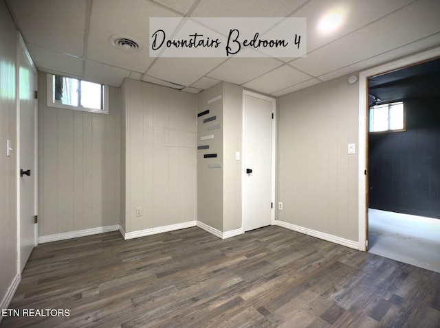 basement with a paneled ceiling, dark hardwood / wood-style flooring, and plenty of natural light