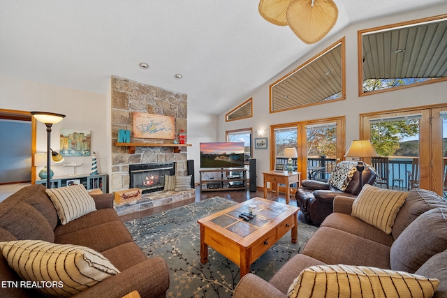 living room featuring wood-type flooring, a stone fireplace, and high vaulted ceiling