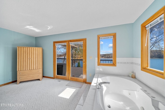 bathroom with tiled bath and a textured ceiling