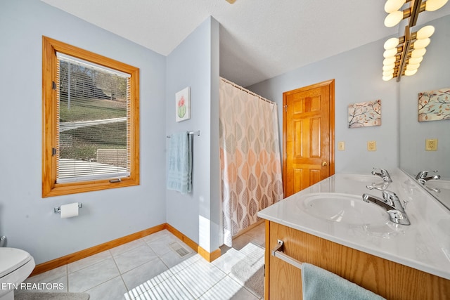 bathroom with tile patterned floors, vanity, a textured ceiling, and toilet