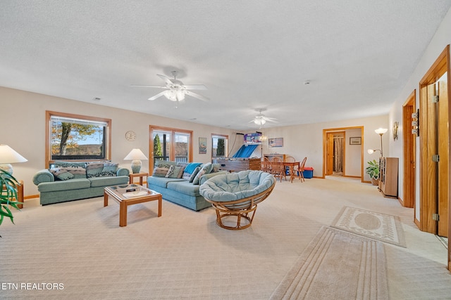 living room featuring ceiling fan, a textured ceiling, and light colored carpet