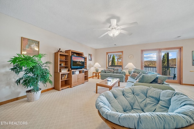 living room with a textured ceiling, light colored carpet, and ceiling fan