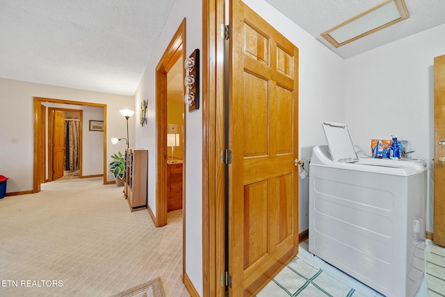 hallway featuring light colored carpet, a textured ceiling, and washer / clothes dryer