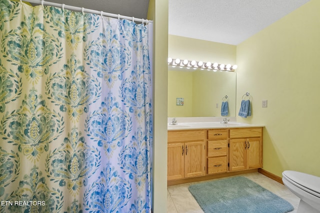 bathroom featuring toilet, vanity, a textured ceiling, and tile patterned floors