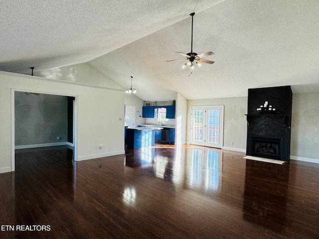 unfurnished living room featuring lofted ceiling, dark wood-type flooring, a textured ceiling, ceiling fan, and a fireplace