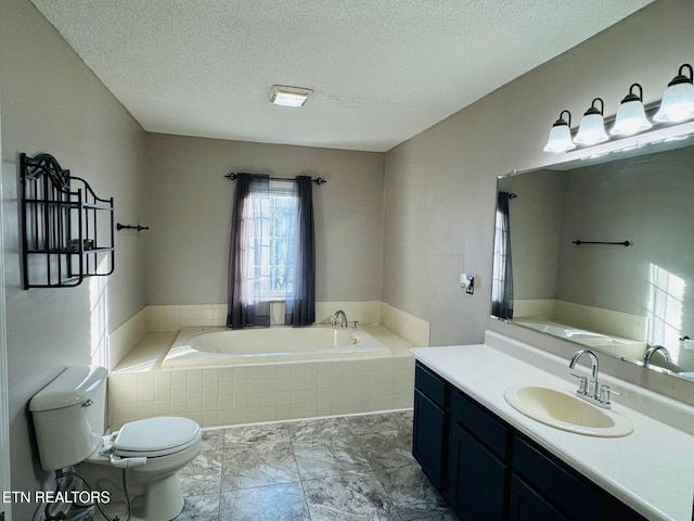 bathroom with vanity, a textured ceiling, toilet, and a relaxing tiled tub