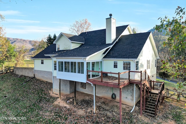 rear view of house featuring a sunroom and a deck with mountain view