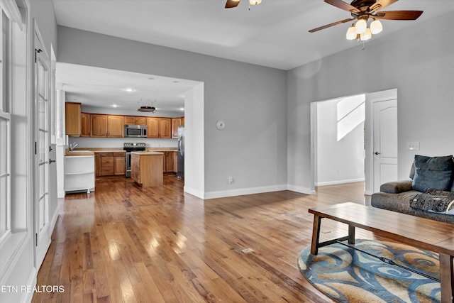 living room featuring light hardwood / wood-style floors, ceiling fan, and sink