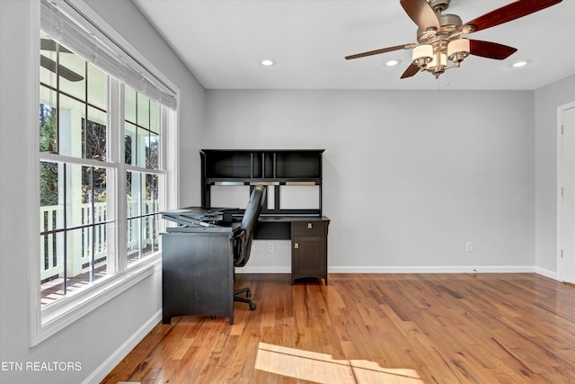 home office with light wood-type flooring, plenty of natural light, and ceiling fan