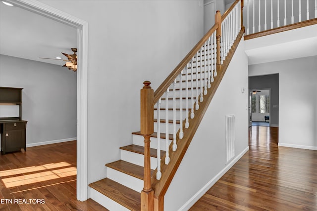 stairs with wood-type flooring and ceiling fan