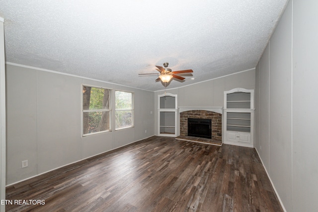 unfurnished living room featuring dark hardwood / wood-style flooring, ornamental molding, a textured ceiling, ceiling fan, and a fireplace