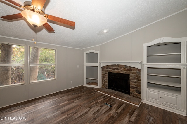 unfurnished living room with a textured ceiling, a stone fireplace, crown molding, and dark hardwood / wood-style floors