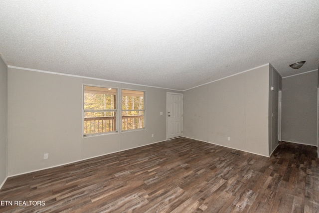 spare room featuring dark hardwood / wood-style flooring, a textured ceiling, and ornamental molding